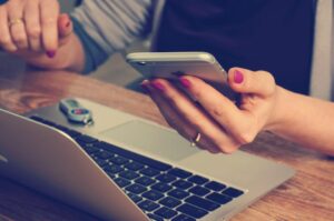 Person holding phone near laptop